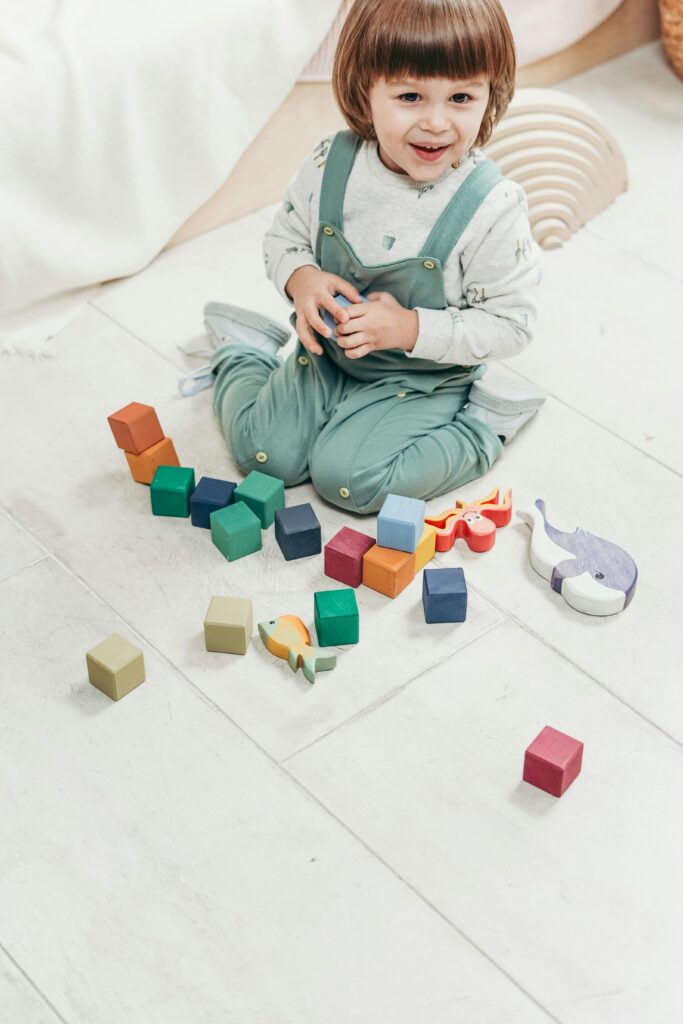 Child in White Long-sleeve Top and Teal Dungaree Trousers Playing With Lego Blocks // Healthier Baby Today