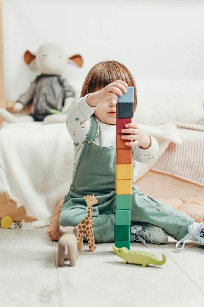 Child in White Long-sleeve Top and Dungaree Trousers Playing With Lego Blocks // Healthier Baby Today