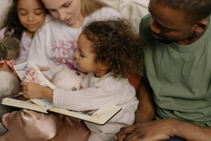 A Young Girl Holding a Photo Album while Sitting Beside Her Family // Healthier Baby Today