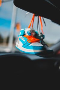 baby shoes tied to car mirror, blue and orange, blurred background // Healthier Me Today