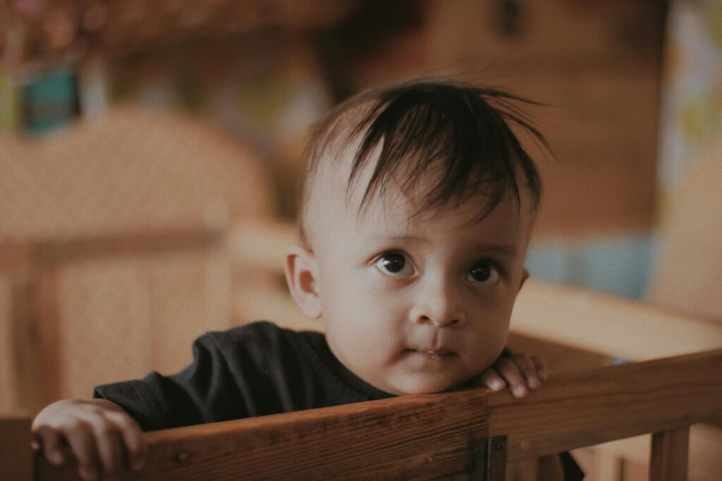 Cute baby standing in wooden crib at home // Healthier Baby Today
