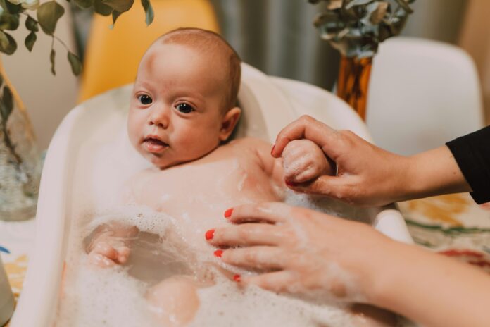 baby wit big eyes, baby bathing in baby bath. bubbles, mom washing // Healthier Baby Today