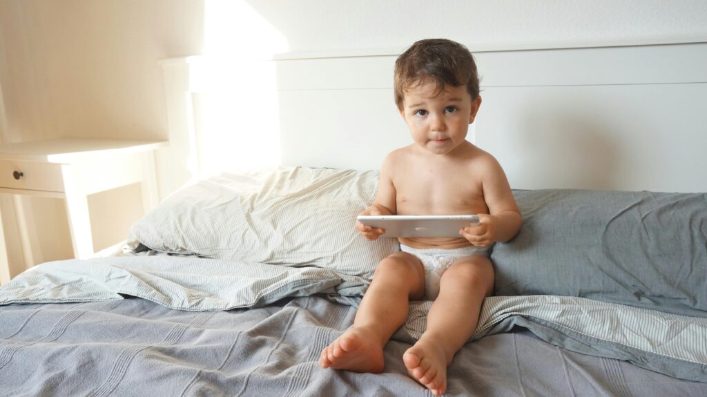 Child Sitting on a Bed Using a Tablet, Screen time // Healthier Baby Today