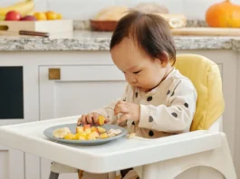 A Toddler Eating Fruits Sitting on the High Chair // Healthier Baby Today