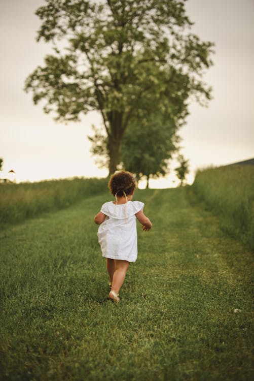 Girl Standing on Grass Field Facing Trees // Healthier Baby Today