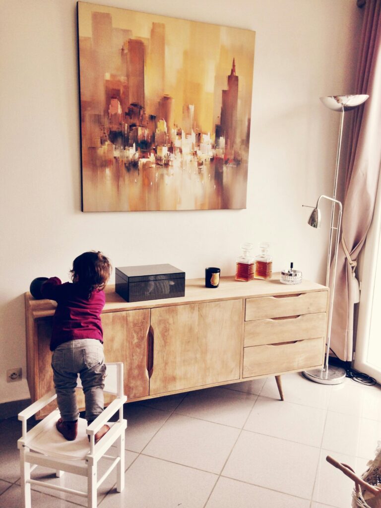 Baby Proofing Cabinets, Toddler Standing on White Chair Beside Sideboard // Healthier Baby Today