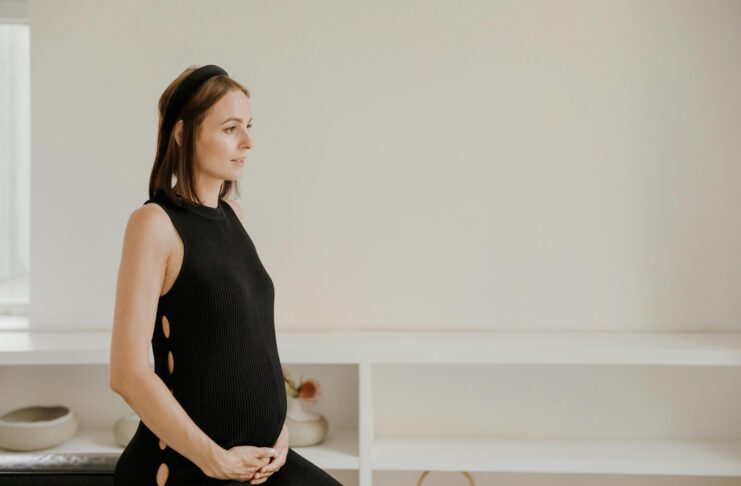 Maternity Shoot of a Woman in Black Tank Dress Holding her Tummy // Healthier Baby Today
