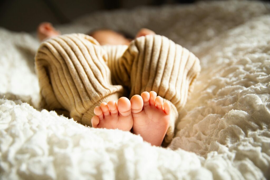 Asphyxiate-Free,  Anonymous barefooted baby sleeping on soft bed in sunlight // Healthier Baby Today