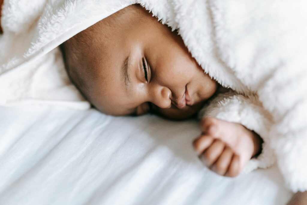 Sleeping newborn black baby lying on bed // Healthier Baby Today