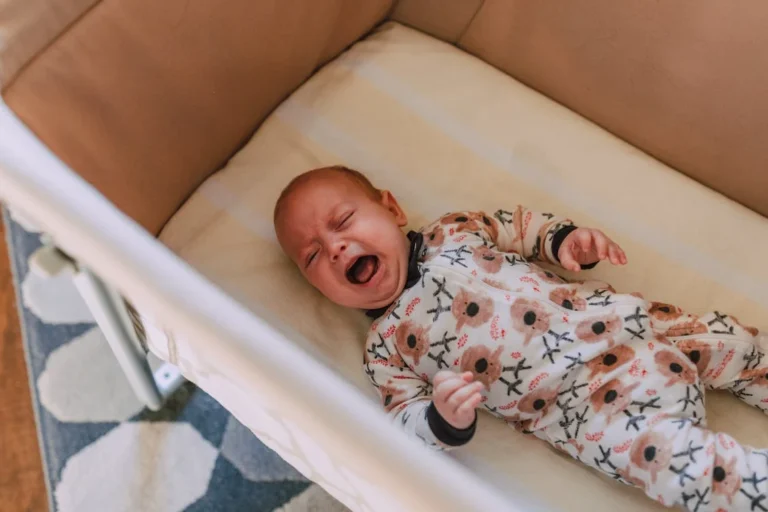 A Baby in Onesie Crying while Lying Down on Crib // Healthier Baby Today