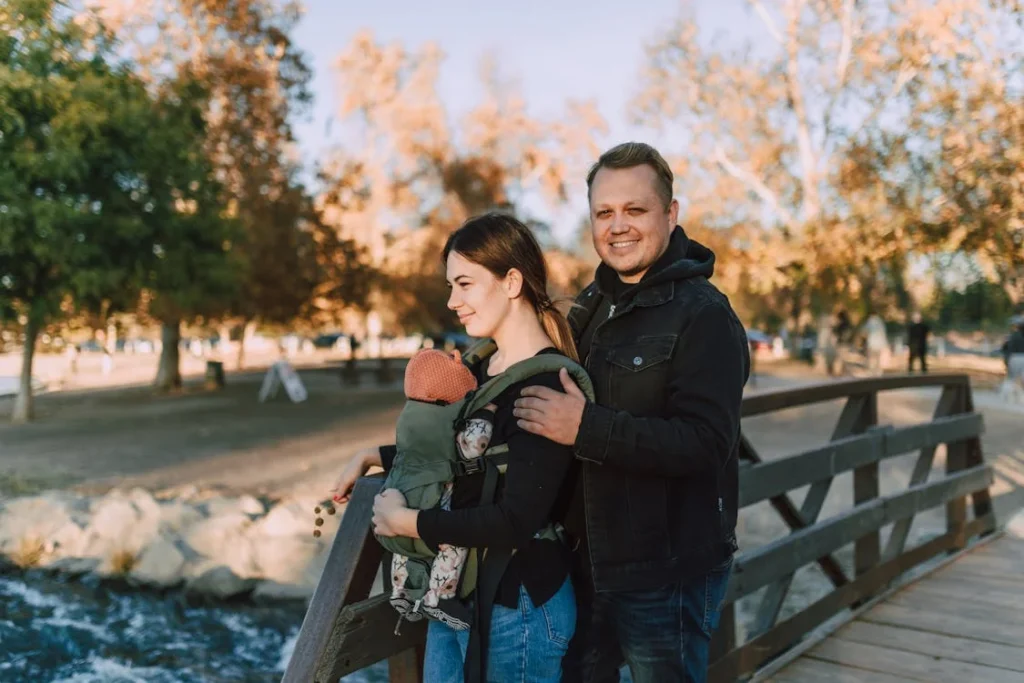 Best Baby Carrier, A Couple in Black Jacket Standing on a Wooden Bridge // Healthier Baby Today