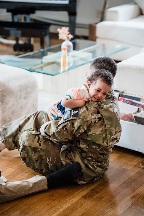 A Soldier Carrying a Child while Sitting on Wooden Flooring // Healthier Baby Today