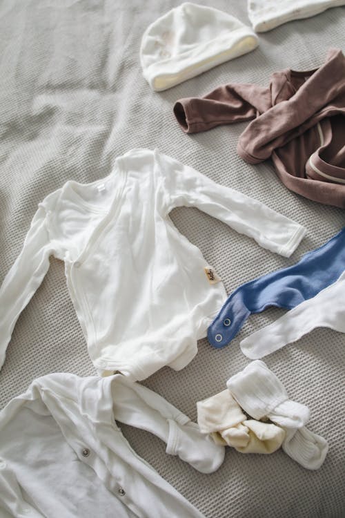 Baby clothes arranged on bed // Healthier Baby Today