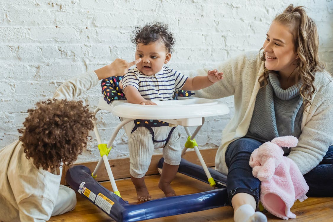 Cheerful mother playing with children, baby walker // Healthier Baby Today