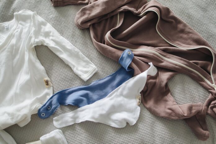 secondhand clothing, Clothes for newborn placed on bed // Healthier Baby Today