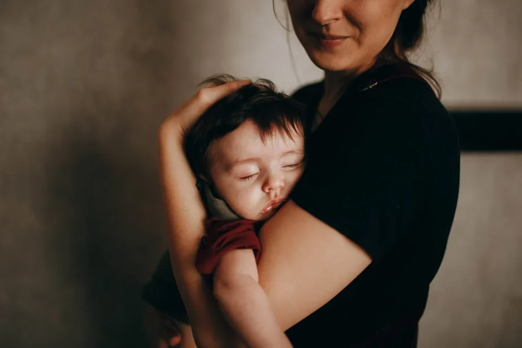 Crop mother with sleepy baby in arms // Healthier Baby Today