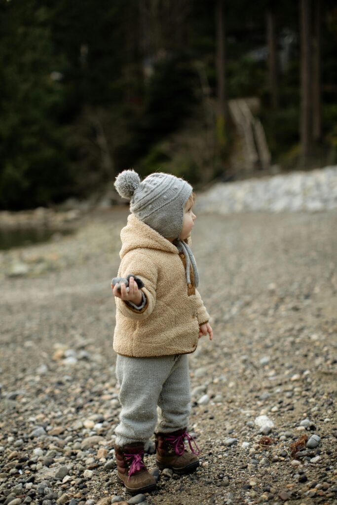 Cute little kid standing on stony ground with pebbles in hand // Healthier Baby Today