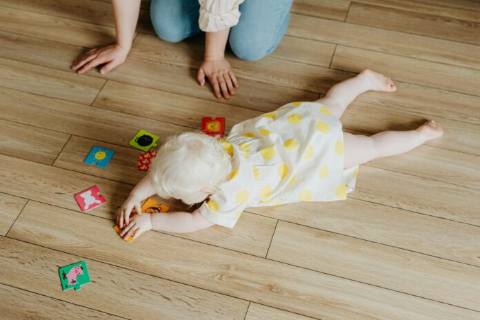 Baby Hates Tummy Time, High-Angle Shot of a Cute Baby Girl in Polka Dot Dress Lying on the Floor while Playing Toys // Healthier Baby Today