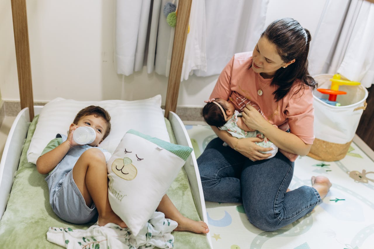 Breastfeeding Tips, Mother Breastfeeding Baby near Son on Bed // Healthier Baby Today