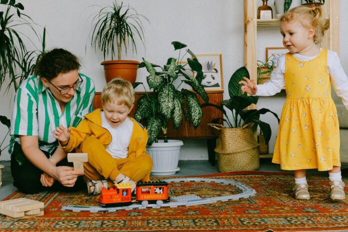 Indoor, Mother and two siblings playing with toy train at home // Healthier Baby Today
