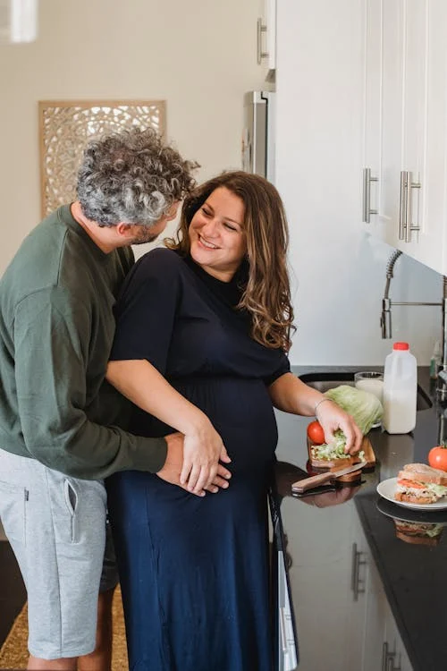 Positive pregnant woman looking at husband while cooking sandwiches // Healthier Baby Today