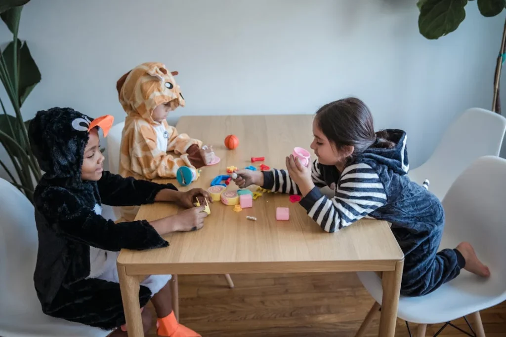 Three Kids in Animal Costumes Playing Toys on a Wooden Table while Sitting // Healthier Baby Today