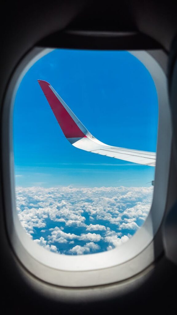 Wing, Sky and Clouds behind Window of Flying Airplane // Healthier Baby Today