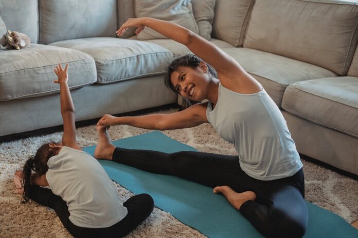 Gymnastic Home Equipment, Cheerful Asian mother and daughter stretching body in living room // Healthier Baby Today