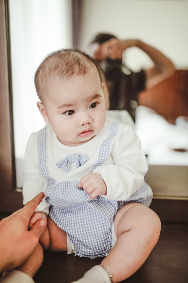 Cute newborn boy sitting on chest in light bedroom // Healthier Baby Today