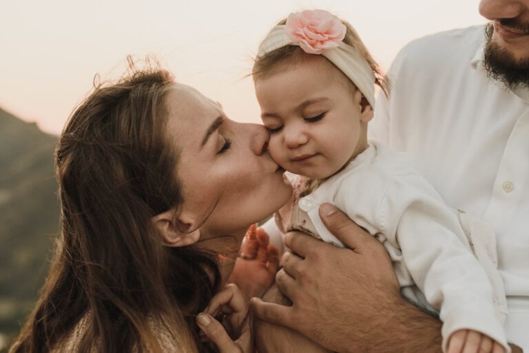 Gentle Parenting, Happy parents hugging and kissing baby // Healthier Baby Today