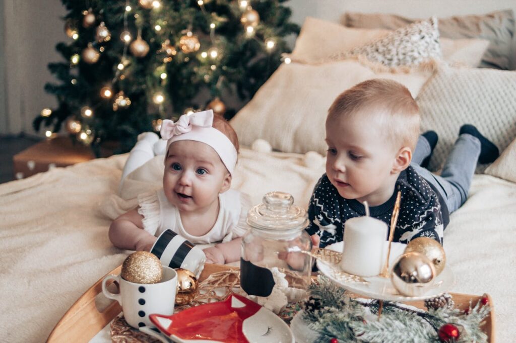 Little children lying on bed near Christmas tree // Healthier Baby Today
