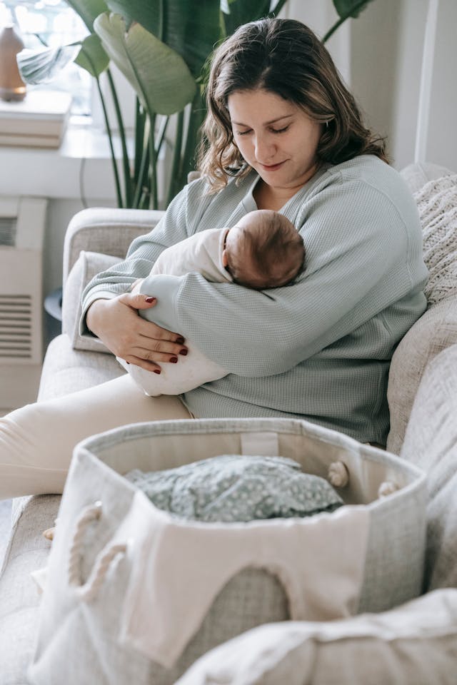 Mother with newborn baby on couch // Healthier Baby Today