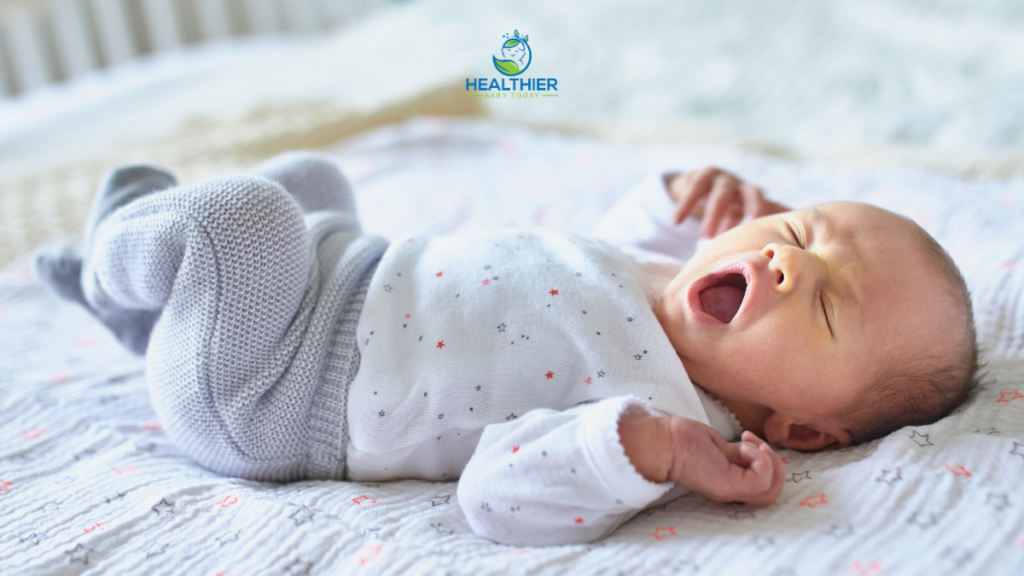 Baby yawning on bed while lying on bed // Healthier Baby Today