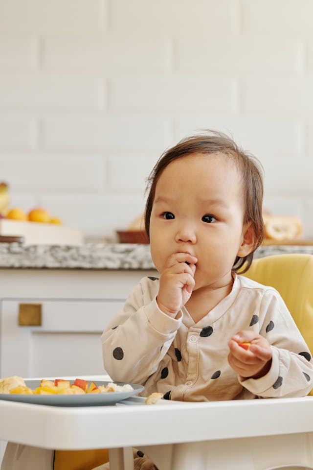 A Child in Polka Dots Clothes Eating Fruits // Healthier Baby Today