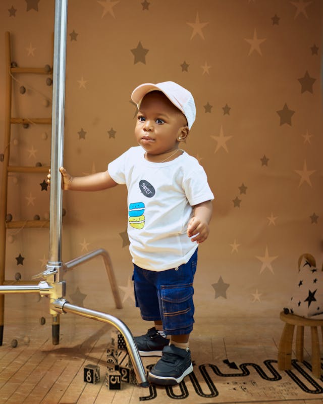 A baby boy standing on a ladder with a star on his shirt // Healthier Baby Today