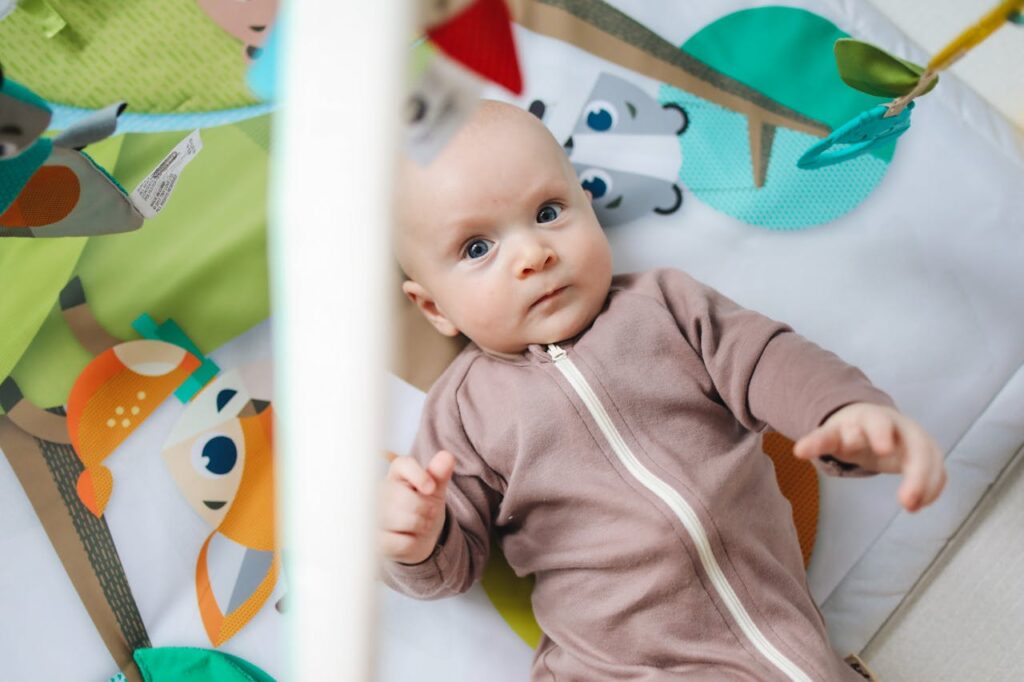 Baby in Pink Zip Up Onesie Lying on Themed Baby mat // Healthier Baby Today