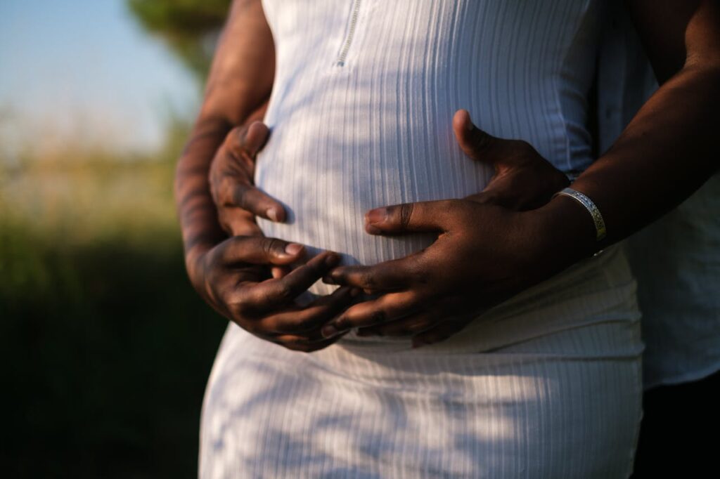 Hands Of A Couple Embracing The Baby Inside Her Growing Belly // Healthier Baby Today