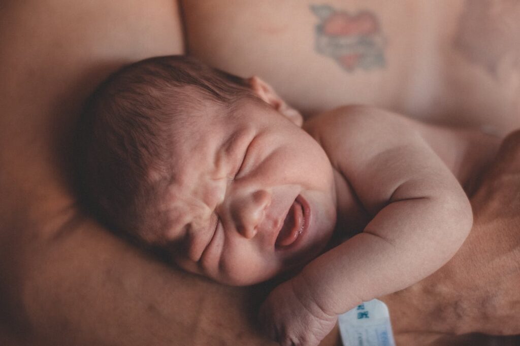 Baby screaming while in the arms of an individual // Healthier Baby Today