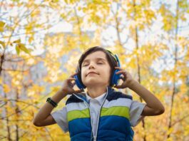 Boy listening Bubble Guppies Them song on blue headphones outside while closing his eyes // Healthier Baby Today