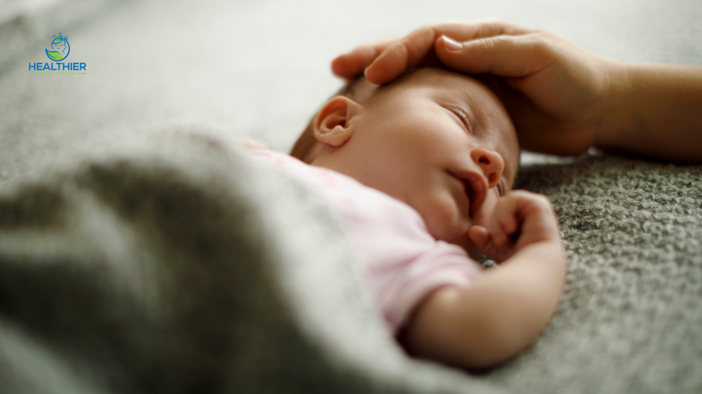 Sleeping baby lying under a blanket while an adult gently checks their forehead with the Healthier Baby Today logo // Healthier Baby Today