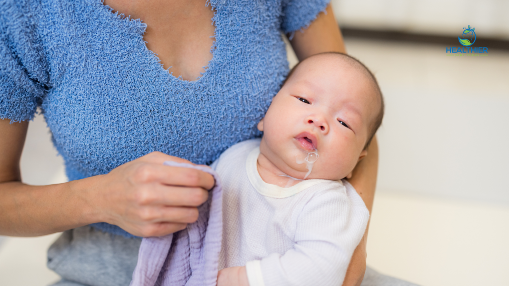Baby being held upright after feeding with milk spit-up visible on their mouth and chin // Healthier Baby Today