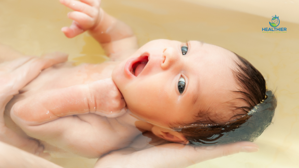 Newborn baby being gently supported during bath time in warm water // Healthier Baby Today