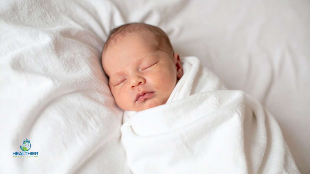 Sleeping newborn wrapped in a white blanket after bath time or bedtime // Healthier Baby Today